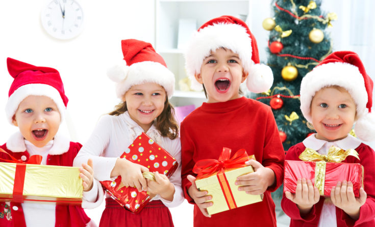 Group of four children in Christmas hat with presents